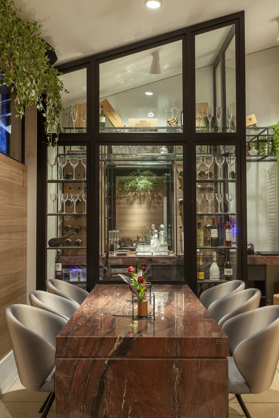 As adegas de vinho também são um sucesso nos restaurantes. O projeto dos arquitetos Elton Casarin e Patricia Bonadia reúne o estilo clássico contemporâneo com um ambiente de tirar o fôlego. O espaço reduzido foi envidraçado para convidar os clientes a apreciarem a escolha de um bom vinho, resultando em um canto de personalidade no projeto com esquadrias largas que demarcam a arquitetura do local. Detalhes que fazem a diferença na experiência do consumidor!