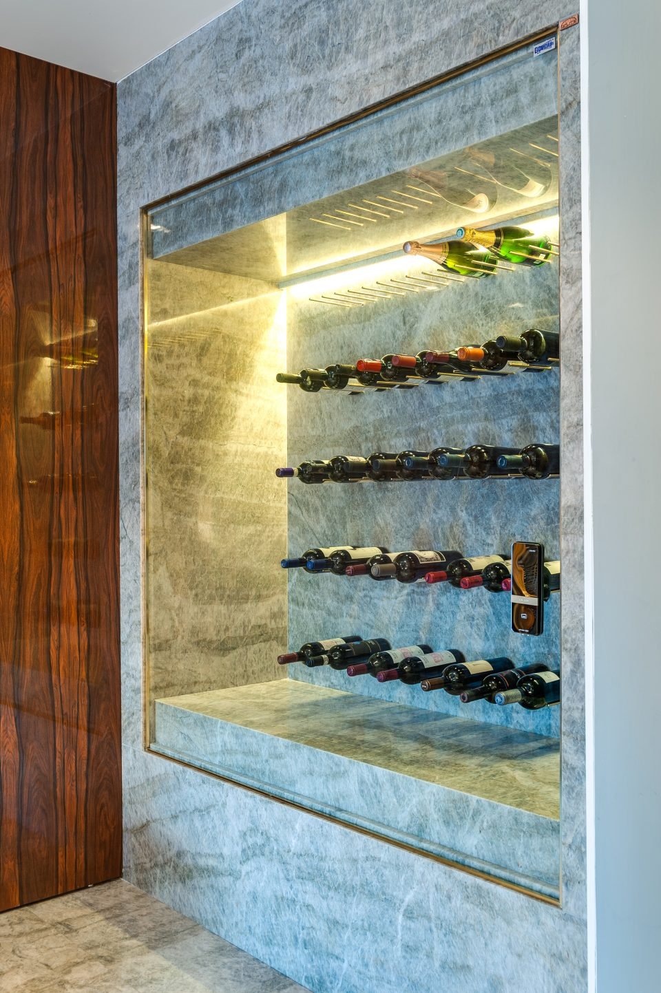 Pensando em obter uma estética clean e integrada no espaço Wine and Relax Time, a adega projetada em um nicho na parede pela arquiteta Milena Niemeyer, fez com que o espaço fosse aproveitado e ainda decorativo, perfeito para se admirar. Além disso, ela conta com acesso eletrônico exclusivo para o colecionador e com a transparência do vidro Cebrace Extra Clear, que ficou despercebido nessa foto para dar suporte às garrafas sem pesar na decoração.